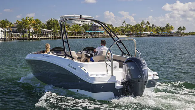 Rear view of a couple approaching shore on a Hurricane SunDeck Sport boat.