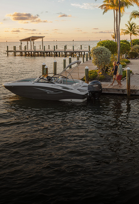 Man and woman approaching parked Hurricane Sundeck Outboard boat from dock. 