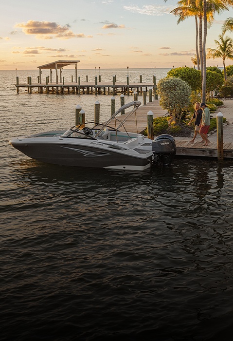 Man and woman approaching parked Hurricane Sundeck Outboard boat from dock. 