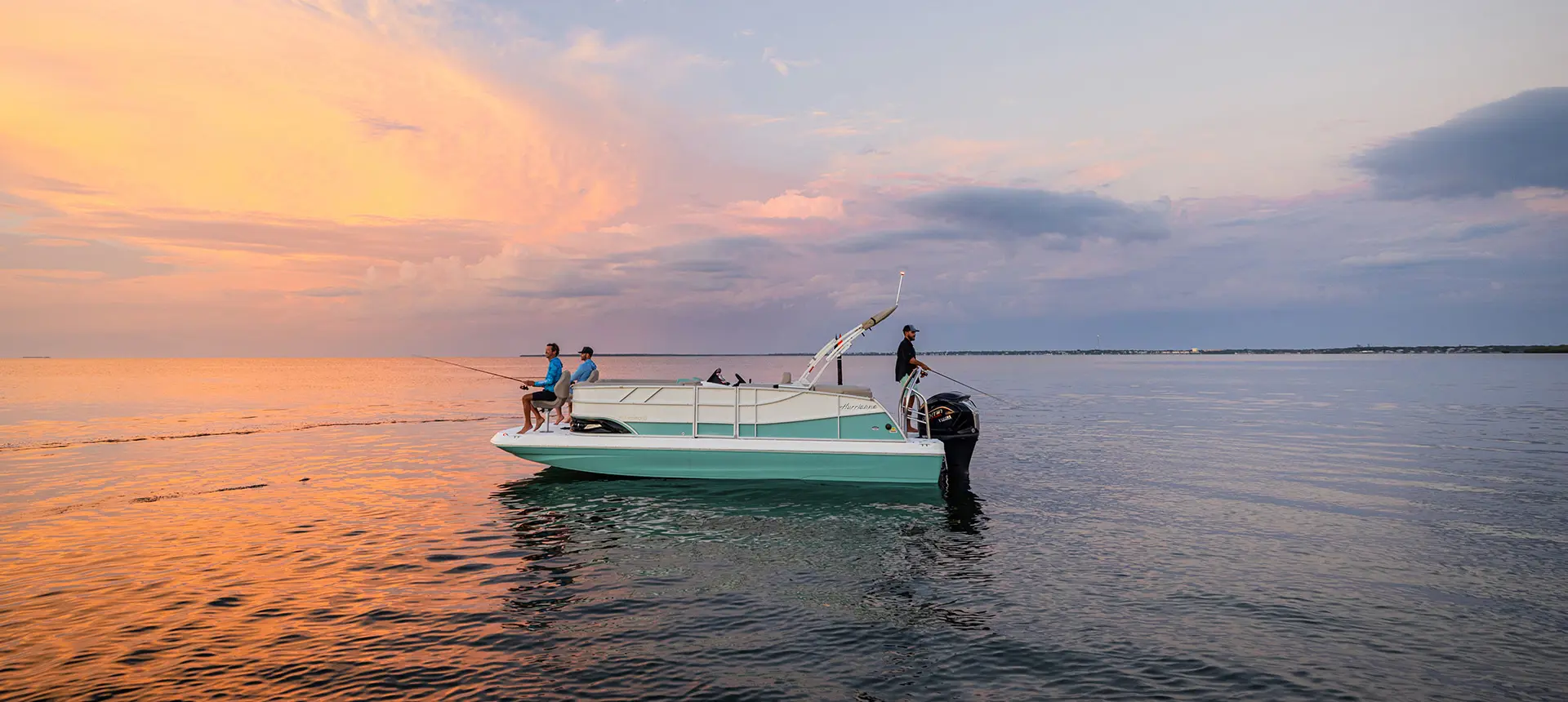 3 people fishing on a Hurricane fishing boat at sunset.