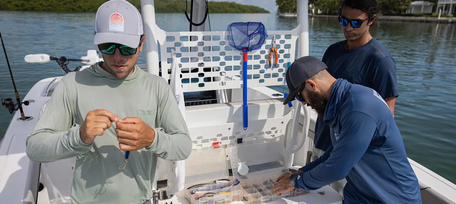 3 men preparing fishing rods to fish off of a Hurricane fishing boat.