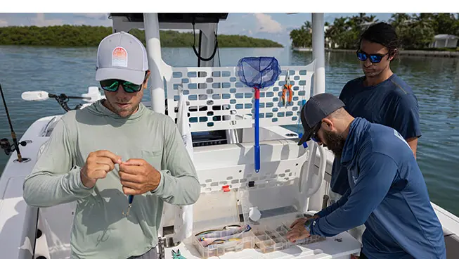 3 men preparing fishing rods to fish off of a Hurricane fishing boat.
