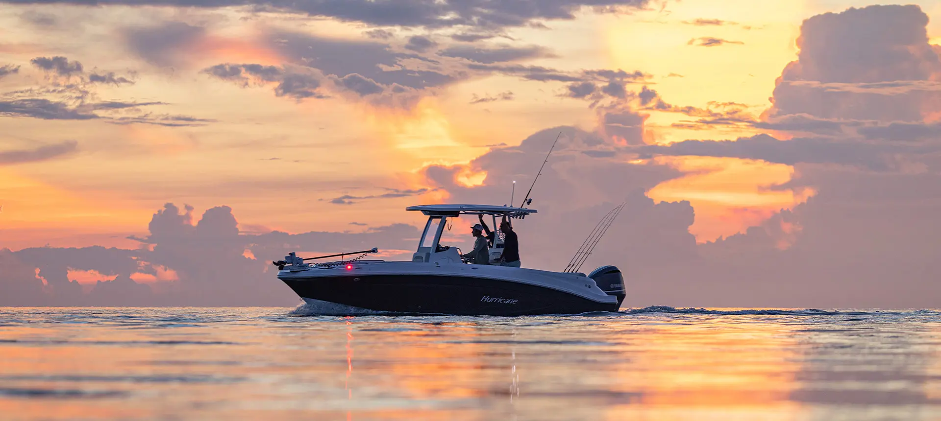 2 men cruising on Hurricane fishing boat at sunset.