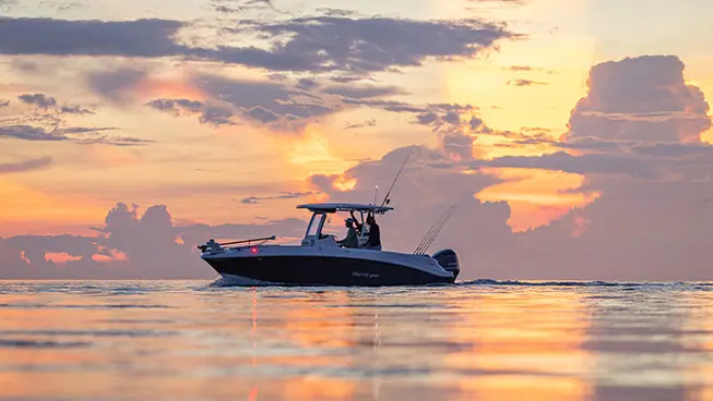 2 men cruising on Hurricane fishing boat at sunset.