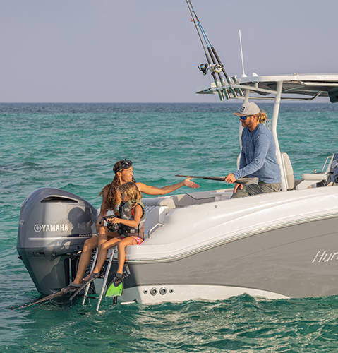 Anchored Hurricane ocean boat with woman and child preparing to swim off the back. 