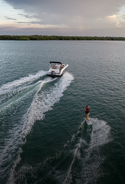 Overhead view of girl getting pulled on wakeboard behind a Hurricane sport boat. 