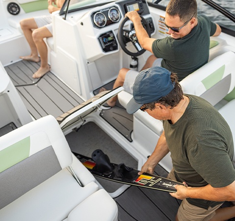 Man removing skis from floor storage on a Hurricane sport boat.