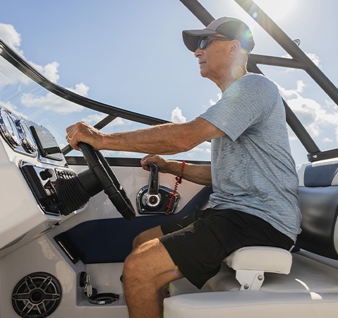 Man sitting in elevated captain's seat on a Hurricane sport boat.