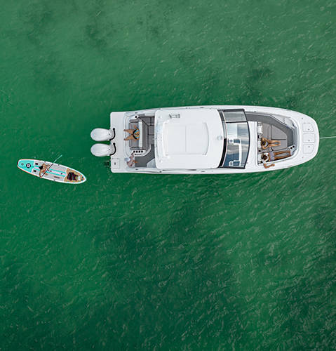 Overhead view of a parked Hurricane Yacht Certified boat with someone floating on a paddleboard nearby. 