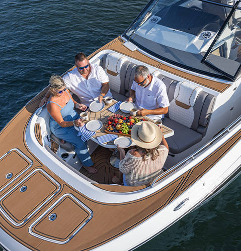 Friends enjoying snacks in spacious seating on the front of a Hurricane Yacht Certified boat. 