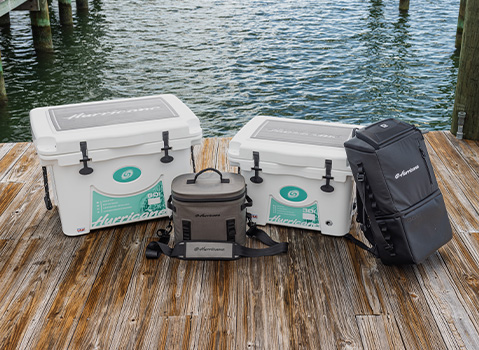 Hurricane‑branded hard and soft‑sided coolers arranged on a dock beside the water.