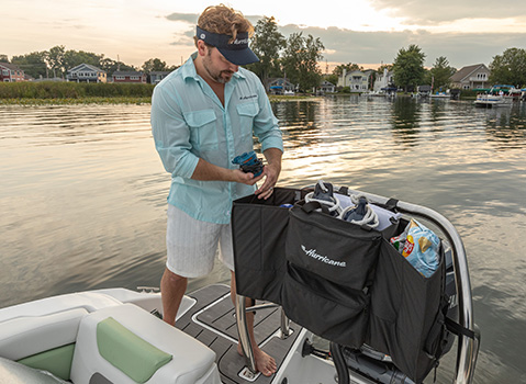 Boater organizing gear in a Hurricane ski tow bar storage bag on the water.