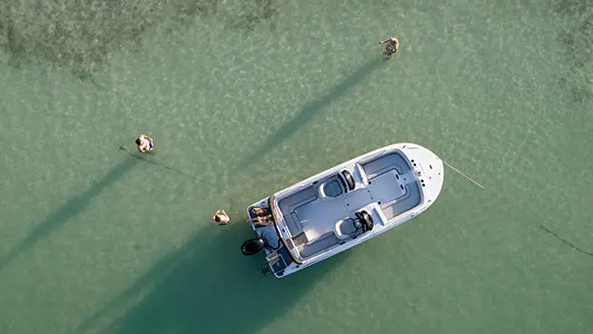 Aerial view of a Hurricane ocean boat floating near a sandbar with people enjoying the water around it.