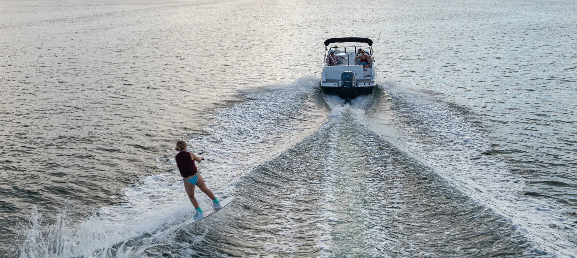 Girl being towed on wakeboard behind a Hurricane sport boat.
