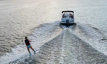 Girl being towed on wakeboard behind a Hurricane sport boat.
