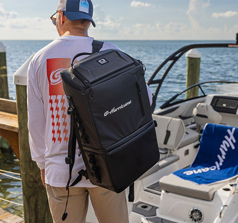 Man standing on dock with a Hurricane cooler backpack. 