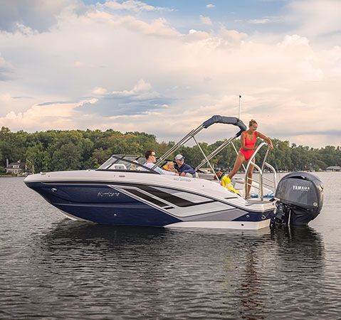 A woman preparing to wakeboard behind a Hurricane deck boat.