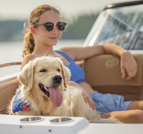A girl and her dog relaxing on the bow seating of a Hurricane deck boat.