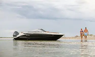 couple taking a walk on the beach with a Hurricane boat aside