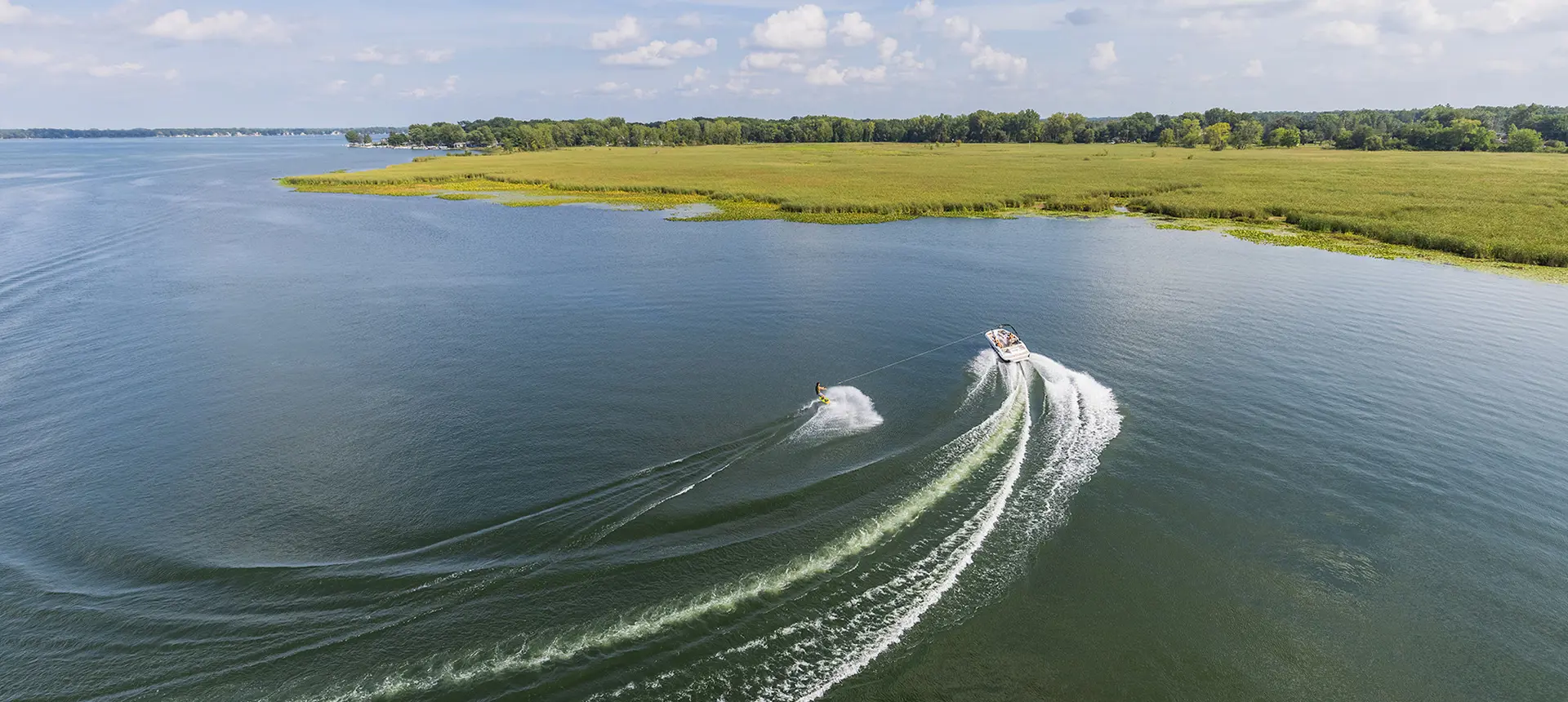 Rear top view of a person wakeboarding on a Hurricane boat in a lake