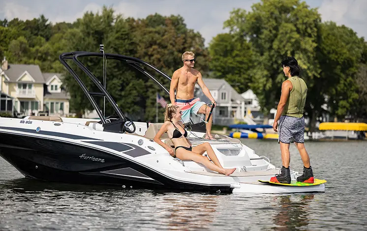 Three friends hanging out on a decked Hurricane boat in a lake