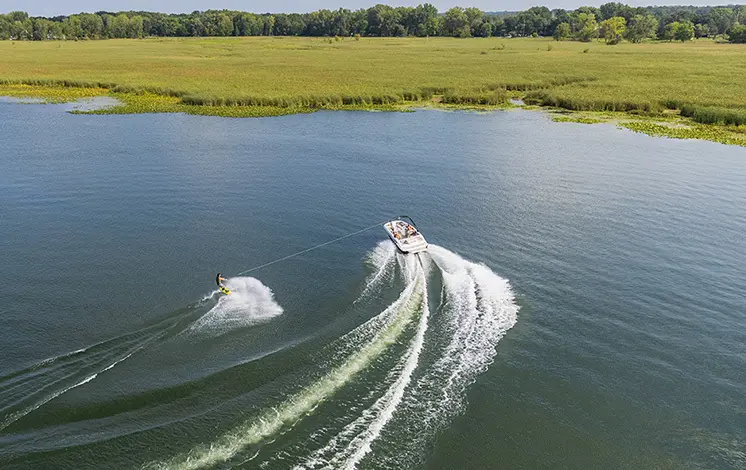 Rear top view of a person wakeboarding on a Hurricane boat in a lake