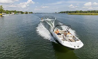 Front view of a Hurricane boat connected to a person wakeboarding on a lake