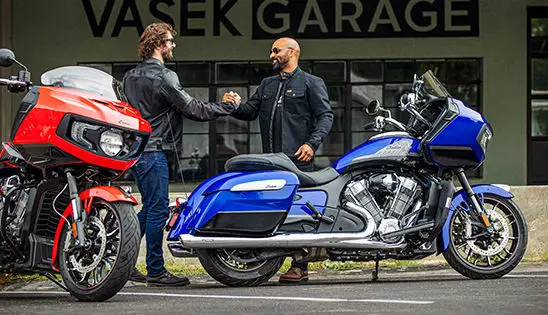 2 riders hanging out by their indian challenger motorcycles