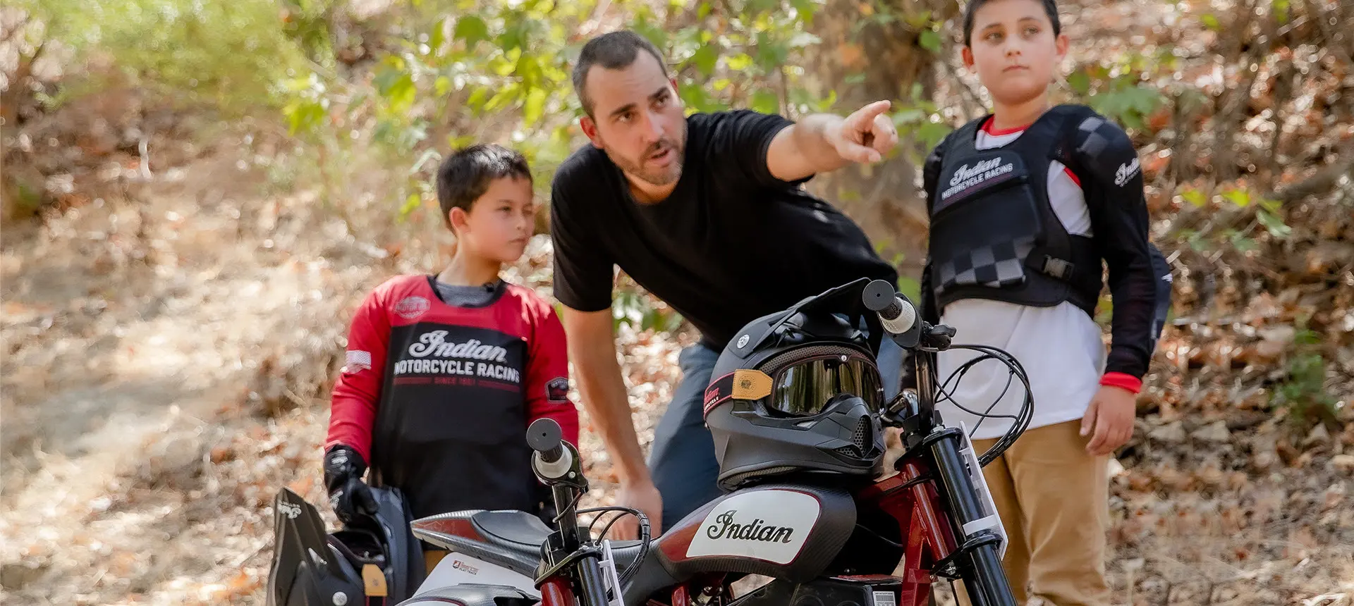 Family gathering around an Indian eFTR Jr and mini bikes