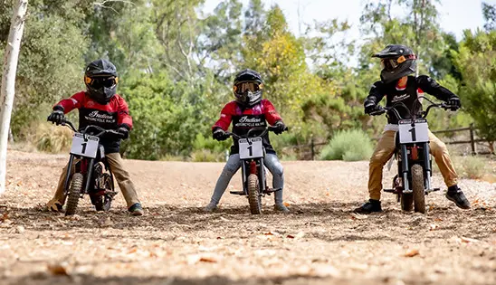 Group of kids riding Indian eFTR mini and Jr bikes on a field