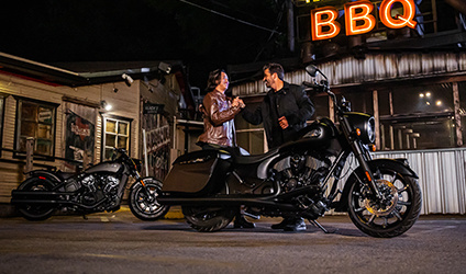 2 riders admiring their parked indian motorcycles at night