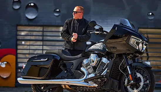 man standing by an indian challenger motorcycle