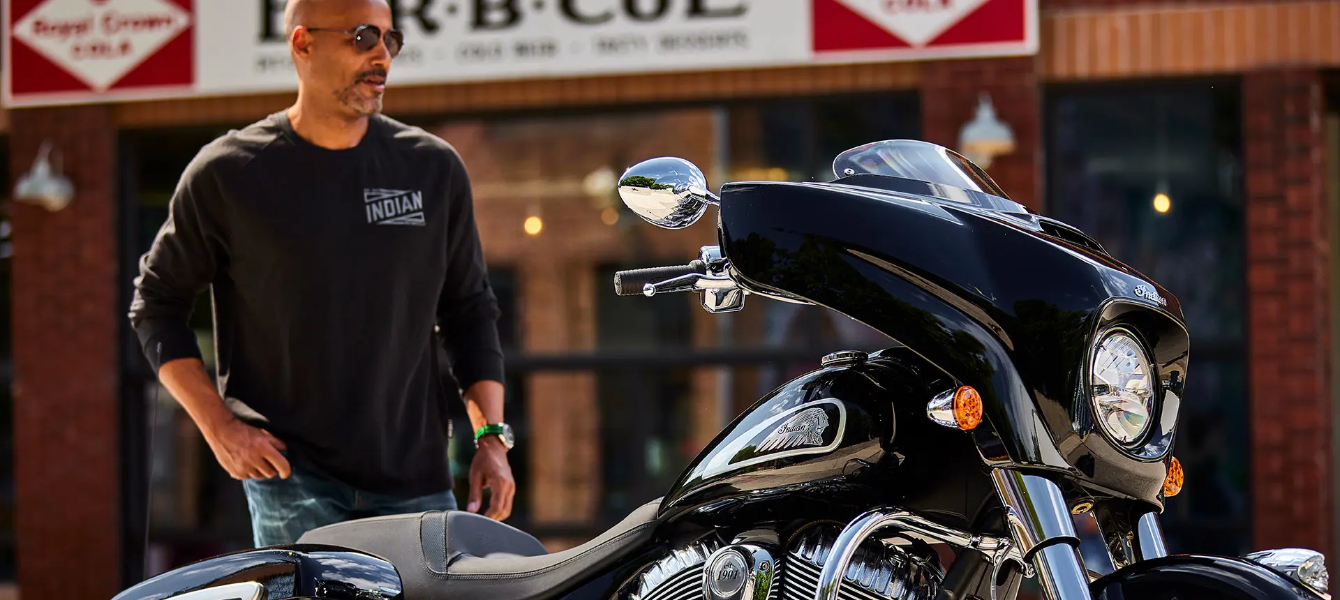 man walking towards a black metallic indian chieftain motorcycle