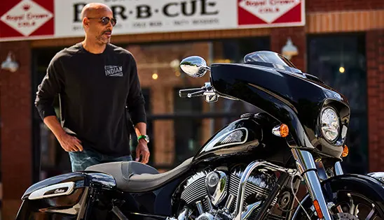 man walking towards a black metallic indian chieftain motorcycle