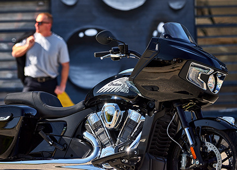 Homme avec un manteau sur son épaule derrière une moto bagger Indian Challenger 2025.