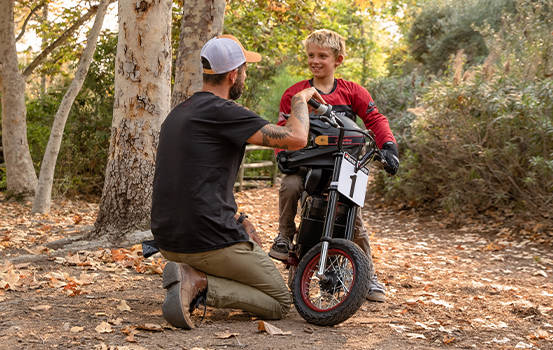 Father teaching son how to ride his Indian eFTR motorcycle. 