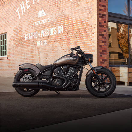 Moto bobber emblématique stationnée dans un terrain vague.