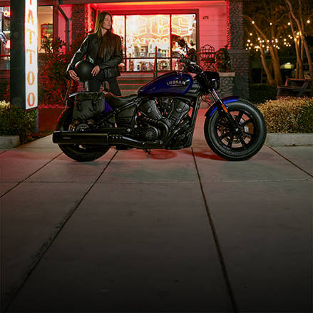 Homme debout à côté d’une moto bobber la nuit.