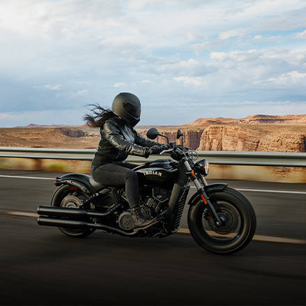 Femme conduisant une moto bobber sur une route.