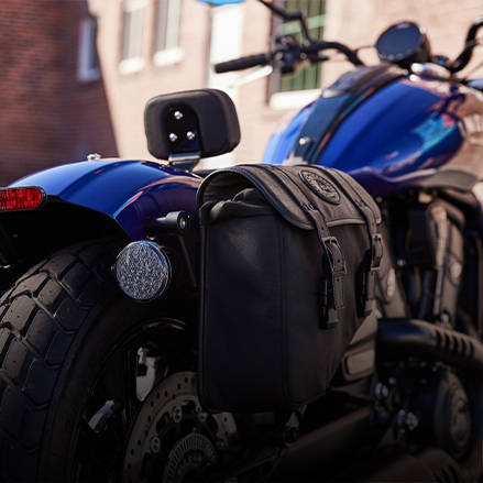 Moto bobber bleue avec une sacoche accessoire en cuir.