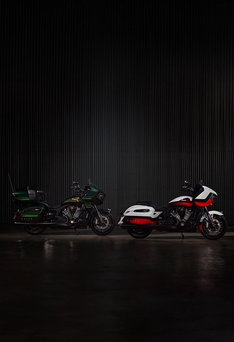Una motocicleta de turismo Indian Pursuit Elite 2025 y una motocicleta bagger Indian Challenger Elite 2025 estacionadas en un garaje tenuemente iluminado.