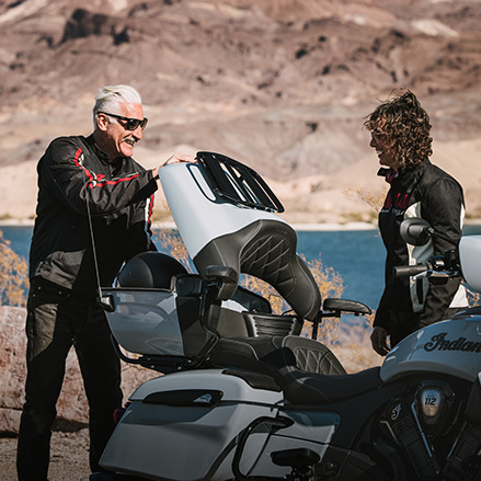 A man grabbing a helmet from the trunk of an Indian touring motorcycle showcasing its ample storage options.
