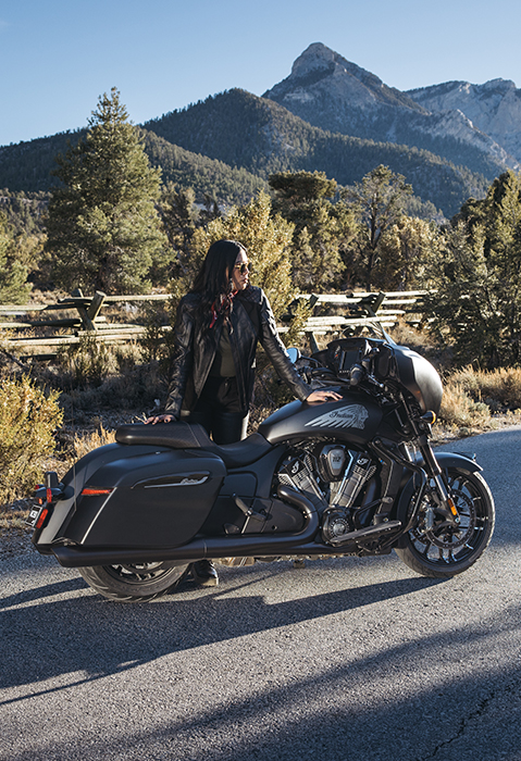 A woman leaning on a 2025 Indian Chieftain PowerPlus Dark Horse with 112 motorcycle.