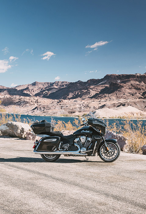 Side profile of a 2025 Indian Roadmaster PowerPlus Limited motorcycle parked on the side of the road near a lake.