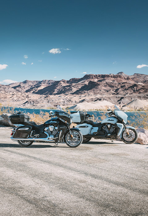 Side profile of a 2025 Indian Roadmaster PowerPlus Dark Horse motorcycle and a 2025 Indian Roadmaster PowerPlus limited motorcycle glistening in the sunlight.