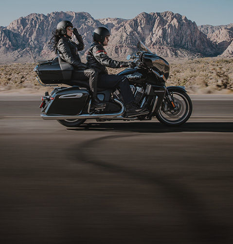 Couple riding on an Indian Motorcycle through mountains while using Motorcycle Ride Assist Technology.