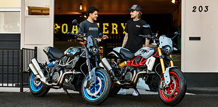 2 men talking near their Indian FTR Standard motorcycles.