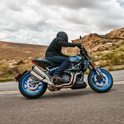 Rider leaning a corner on an Indian FTR Sport standard-style motorcycle on a highway.