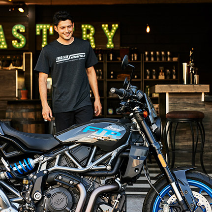 Man standing behind an Indian FTR Sport standard-style motorcycle.