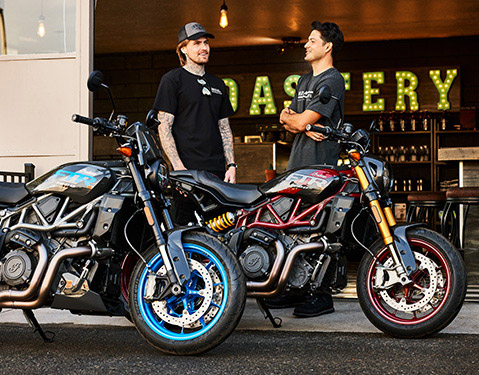 2 men standing behind their Indian FTR Sport and FTR R Carbon standard-style motorcycles.